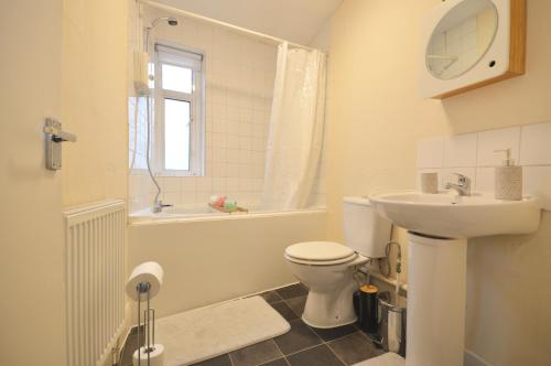 a bathroom with a toilet and a sink and a tub at Curve Apartments in London