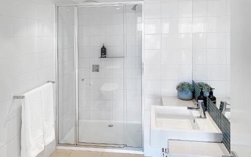 a white bathroom with a shower and a sink at Golfclub Townhouse Apollo Blue 7 in Apollo Bay