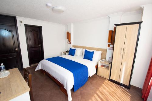 a bedroom with a large bed with blue pillows at Hotel Plaza Victoria in Ibarra