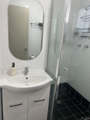 a bathroom with a sink and a shower with a mirror at Batemans Bay North Bush Cottages in Benandarah
