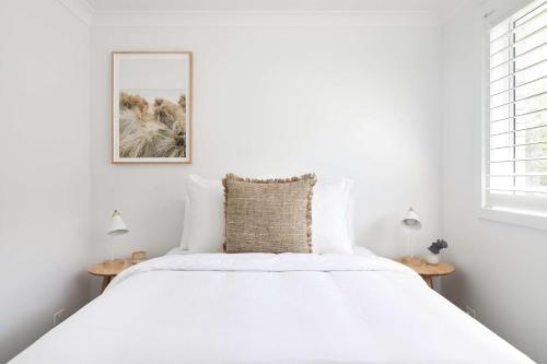 a white bedroom with a large bed with white sheets at No 3 Luana in Nelson Bay