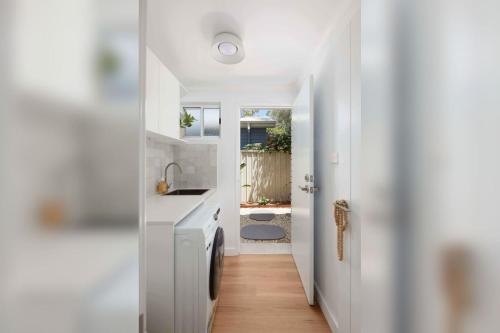 a kitchen with white counters and a sink and a hallway at No 3 Luana in Nelson Bay
