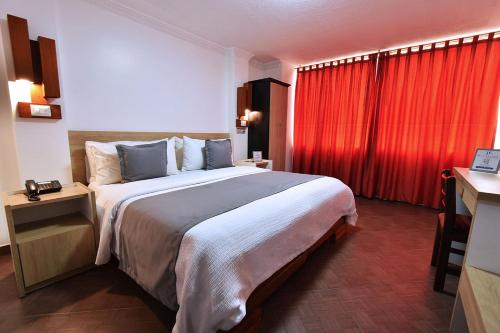 a bedroom with a large bed with a red curtain at Hotel Plaza Victoria in Ibarra