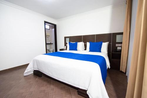 a bedroom with a large bed with blue pillows at Hotel Plaza Victoria in Ibarra