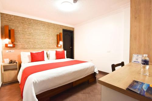 a bedroom with a large bed and a desk at Hotel Plaza Victoria in Ibarra