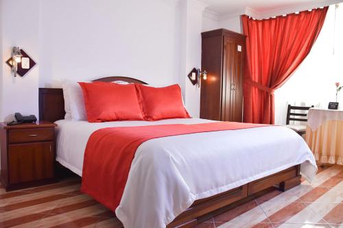 a bedroom with a large bed with red pillows at Hotel Plaza Victoria in Ibarra