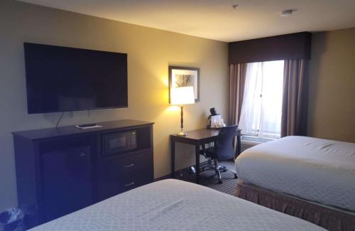 a hotel room with a bed and a desk with a television at Best Western Plus Mishawaka Inn in South Bend