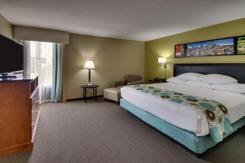 Drury Inn & Suites Houston The Woodlands في ذا وودلاندس: غرفة فندقية بسرير كبير وتلفزيون بشاشة مسطحة