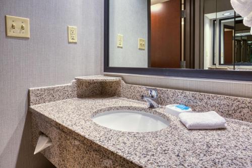 Drury Inn & Suites St. Louis Airport في إدموندسون: منضدة الحمام مع الحوض والمرآة