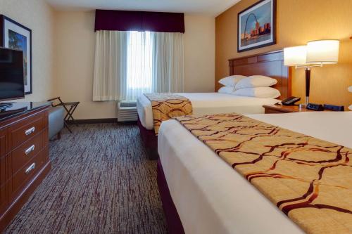 a hotel room with two beds and a flat screen tv at Drury Inn & Suites St. Louis Forest Park in Saint Louis