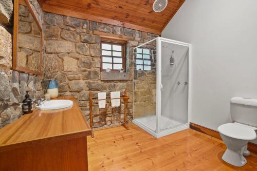 a stone bathroom with a shower and a sink at Breakfast Creek Cottage in Port Fairy