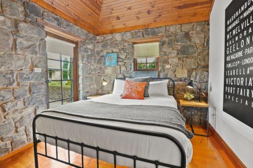 a bed in a room with a stone wall at Breakfast Creek Cottage in Port Fairy