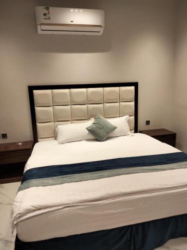 1 dormitorio con 1 cama grande con sábanas y almohadas blancas en مساكن الريان, en Riad