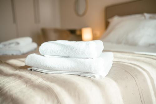 a pile of towels sitting on top of a bed at Designer Stay 100sqm, Wood & Marble , 5min to Sea in Platánion
