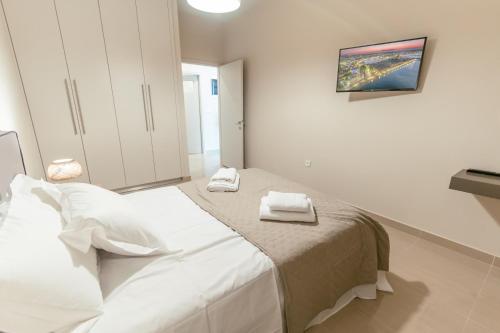 a white bedroom with a bed with towels on it at Designer Stay 100sqm, Wood & Marble , 5min to Sea in Platánion
