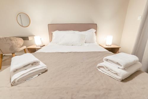 a bedroom with a white bed with towels on it at Designer Stay 100sqm, Wood & Marble , 5min to Sea in Platánion