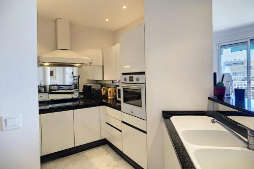 a kitchen with white cabinets and a sink and a window at Superb 2 bedroom apartment with sea view on the Croisette in Cannes