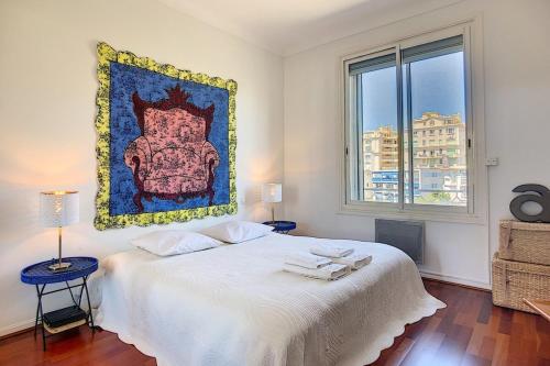 une chambre avec un lit blanc avec un tableau sur le mur dans l'établissement Superb 2 bedroom apartment with sea view on the Croisette, à Cannes