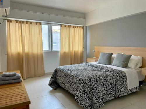 a bedroom with a black and white bed and a window at Calido departamento en Mendoza in Mendoza