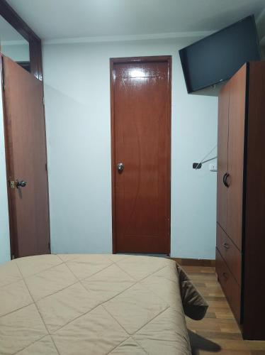 Yuraq Wasi Hostal في اياكوتشو: غرفة نوم بسرير وباب خشبي