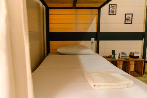 een slaapkamer met een bed met een handdoek erop bij Salty Enthusiasts Share House & Villas in Santa Teresa Beach
