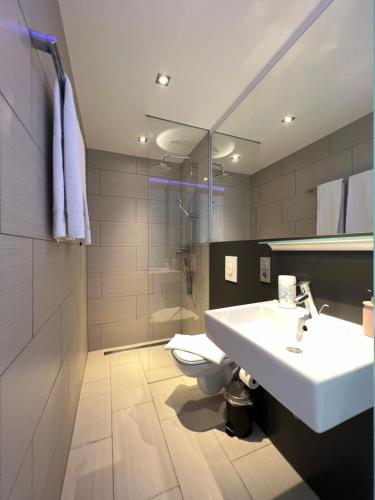 a bathroom with a sink and a toilet and a shower at The East Apartment by Rabe - Netflix & Coffee & Parkplatz in Karlsruhe