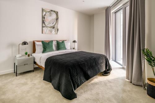 Un dormitorio con una cama con almohadas verdes y una ventana en Urban Rest Battersea Apartments, en Londres