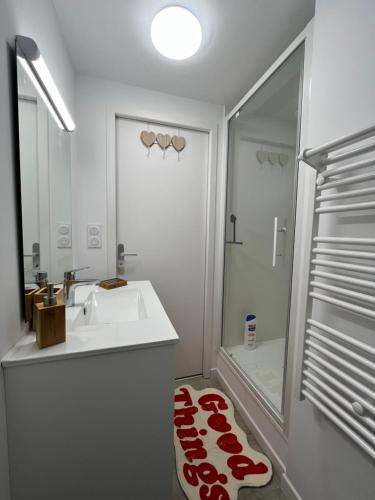 une salle de bain blanche avec un lavabo et une douche dans l'établissement Appartement confort à Cholet, à Cholet