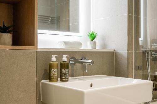 a bathroom sink with two bottles on top of it at Urban Rest Battersea Apartments in London