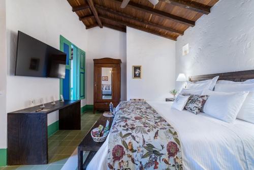 a bedroom with a large bed and a television at Casa Cedrela Hotel Boutique by HMC -Cauca Viejo- Mayores de 14 años in Jericó