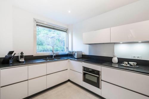 une cuisine avec des armoires blanches et une fenêtre dans l'établissement Very nice 2 bedroom apartment in the center of Cannes completely renovated, à Cannes