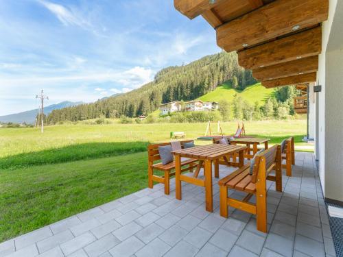 a patio with wooden tables and chairs and a field at Chalet Joep in Wald im Pinzgau