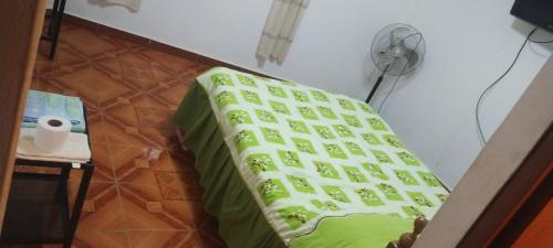 a bed in a room with a green blanket at Punto surf terrace in Pacasmayo