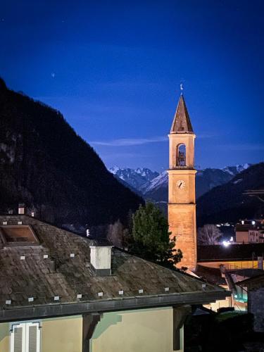 a clock tower on top of a building with a mountain at Balcone sulla Valmalenco - Vista mozzafiato in Chiesa in Valmalenco
