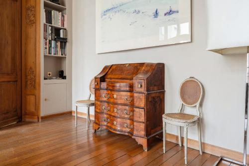 une chambre avec une commode en bois et deux chaises dans l'établissement Appartement Mewes - Welkeys, à Paris