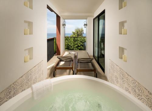 a bathroom with a tub and a table and chairs at Avista Grande Phuket Karon - MGallery in Karon Beach