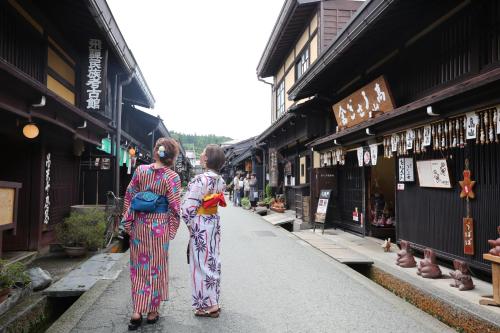 two women are walking down a narrow street at Hida Takayamasan no machi House - Vacation STAY 98088v in Takayama