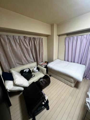 a room with a bed and a couch with luggage at Big houz in Sendai