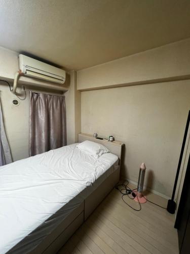 a bed in a small room with a air conditioner at Big houz in Sendai
