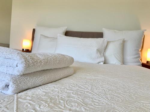- un lit avec des draps et des oreillers blancs et 2 lampes dans l'établissement Sunny, Spacious mountain views, Holiday home, à Lenah Valley