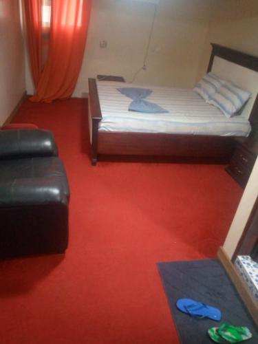 a bedroom with a bed and a red floor at Hotel La Rochelle in Bonamakolo