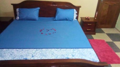 a bedroom with a blue bed with blue sheets and blue pillows at Hotel La Rochelle in Bonamakolo