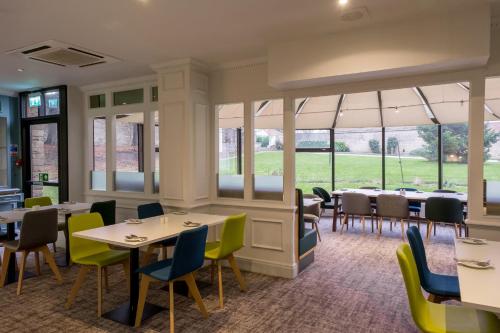 a restaurant with tables and chairs and windows at Holiday Inn Doncaster A1- M Jct 36 by IHG in Doncaster
