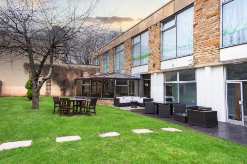a building with a table and chairs in the grass at Holiday Inn Doncaster A1- M Jct 36 by IHG in Doncaster