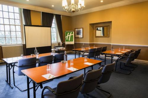 a conference room with tables and chairs and a screen at Holiday Inn Doncaster A1- M Jct 36 by IHG in Doncaster