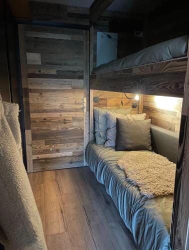 een bed in een kamer met een houten muur bij Charming studio with terrace and garden in Praz-sur-Arly