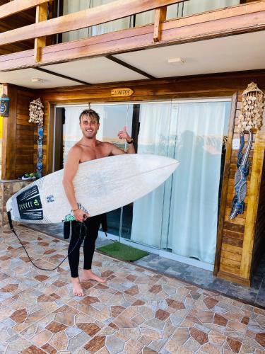 a man holding a surfboard in front of a house at Casa Lobos in Lobitos