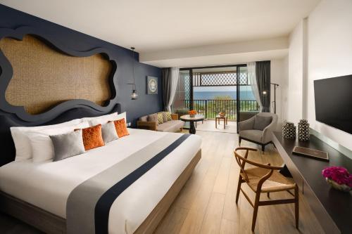 a bedroom with a large bed and a living room at Avista Grande Phuket Karon - MGallery in Karon Beach