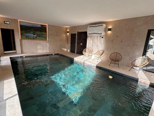 - une grande piscine avec 2 chaises dans une chambre dans l'établissement Luxe et détente : Lodge avec SPA privatif et accès piscine, golf, et aire de jeux. - FR-1-582-39, au Chambon-sur-Lignon