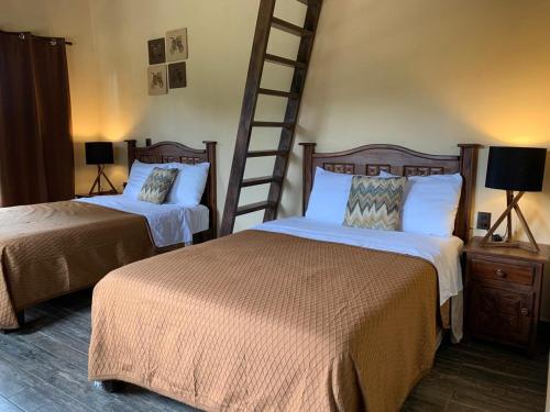 a hotel room with two beds and a ladder at Cabaña No.3 Puerta del Bosque Mazamitla. in Mazamitla